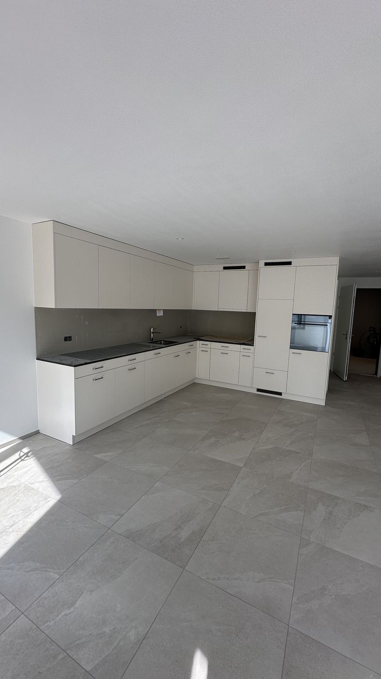 Offene Küche mit grossformatigem Plattenboden in einer Neubauwohnung